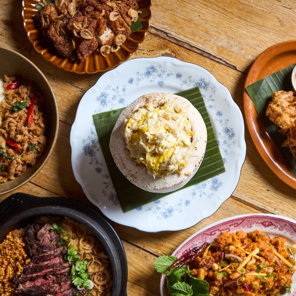 Overhead view of various Thai dishes, including fried chicken, rice with egg, and crab in a coconut.